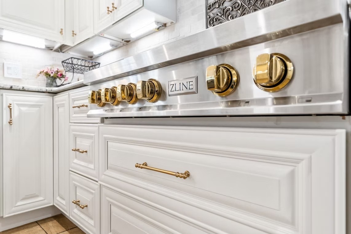 Detail of ZLINE range with gold knobs and Pearl White cabinets