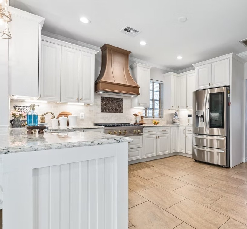 Pearl White kitchen with granite island, copper hood and stainless steel refrigerator