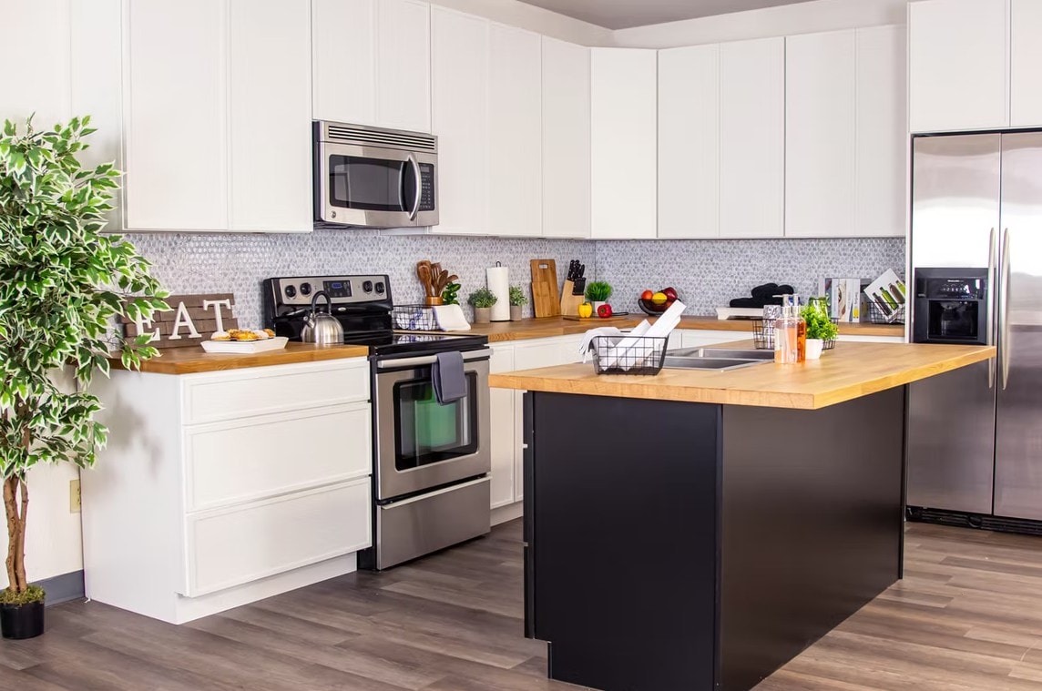 Slim Shaker Alabaster kitchen with stainless range, black island and EAT sign decor