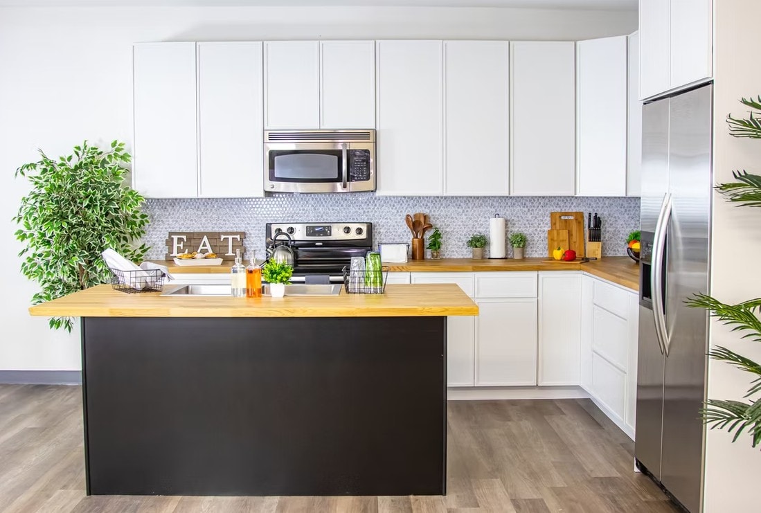 Front view of Slim Shaker Alabaster kitchen with microwave, range and stainless refrigerator