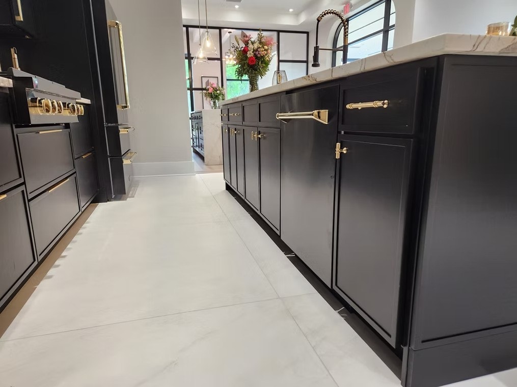 Side view of Slim Shaker Ebony kitchen with black island, gold hardware and white floor