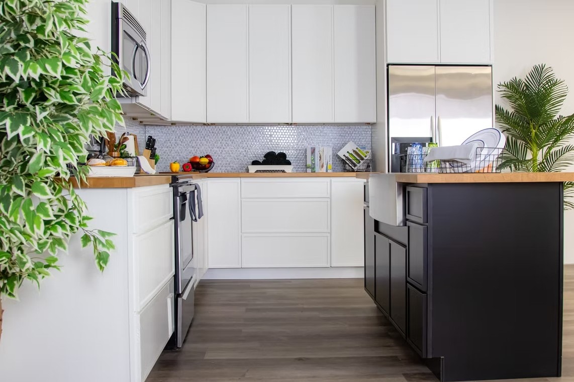 Slim Shaker Ebony kitchen with white upper cabinets, black island and tropical plants