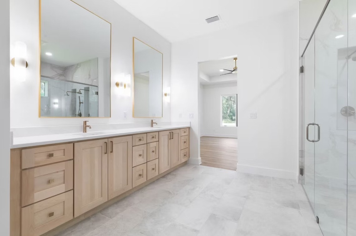 Bathroom with light maple Versa Shaker vanity, gold mirrors and glass shower