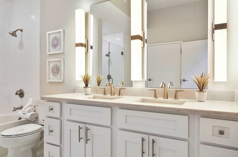 Detail of White Shaker double vanity with gold hardware and lighted mirrors